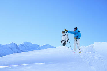 Mature man gesturing to woman standing in snow under sky - JAHF00231