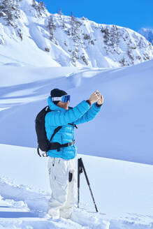 Älterer Mann im Schnee beim Fotografieren an einem sonnigen Tag - JAHF00234
