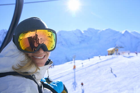 Happy woman with ski goggles on sunny day - JAHF00244
