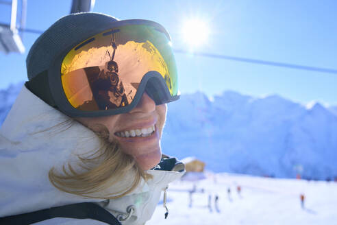 Smiling woman with ski goggles on sunny day - JAHF00245