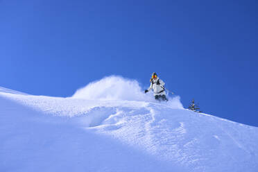 Ältere Frau beim Skifahren unter blauem Himmel - JAHF00251