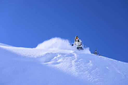 Mature woman skiing under blue sky - JAHF00251