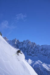 Man skiing downhill under blue sky - JAHF00255