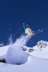Skifahrer, der auf einem Berg aus dem Schnee springt - JAHF00261