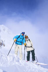 Couple in ski wear standing on powdered snow - JAHF00267