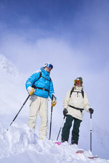 Mature couple standing on snow covered mountain - JAHF00268