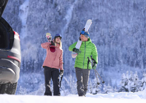 Man and woman walking with skis and poles in front of mountain - JAHF00318