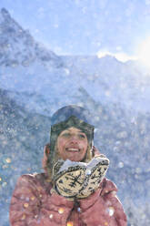 Happy woman with snow standing in front of mountain - JAHF00321