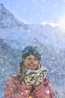 Glückliche Frau mit Schnee vor einem Berg stehend - JAHF00321