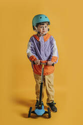Lächelnde niedlichen Jungen mit Push-Roller gegen gelben Hintergrund - VSNF00577