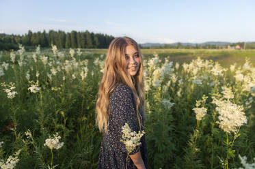 Beautiful woman standing amidst flowering plants in field - VBUF00276