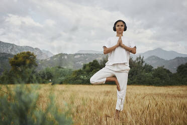 Woman with hands clasped standing in tree pose - ANNF00025