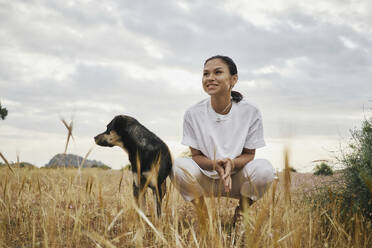 Glückliche Frau mit Hund auf einem Feld - ANNF00027