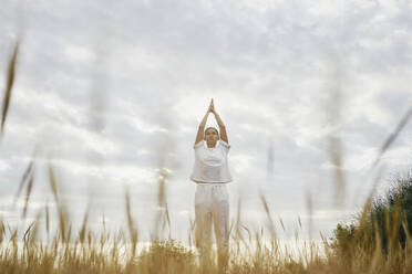 Woman with hands clasped standing in under sky - ANNF00029