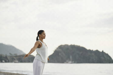 Woman practicing yoga in front of sea - ANNF00031
