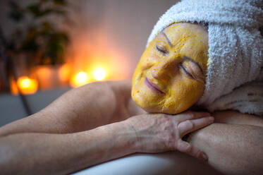 Happy senior woman with beauty face mask in bath tub at home, relaxing with eyes closed. - HPIF08004