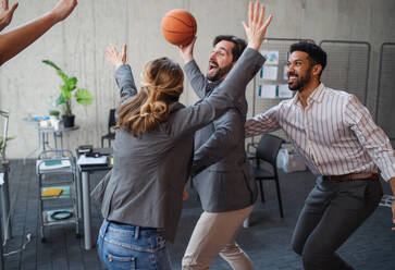 Eine Gruppe fröhlicher junger Geschäftsleute spielt Basketball im Büro und macht eine Pause. - HPIF08019