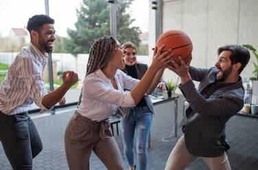 A group of cheerful young businesspeople playing basketball in office, taking a break concept. - HPIF08020