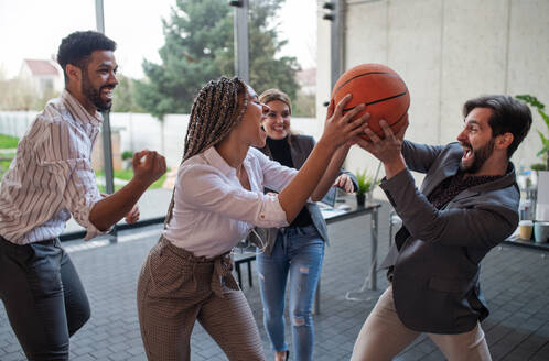 Eine Gruppe fröhlicher junger Geschäftsleute spielt Basketball im Büro und macht eine Pause. - HPIF08020