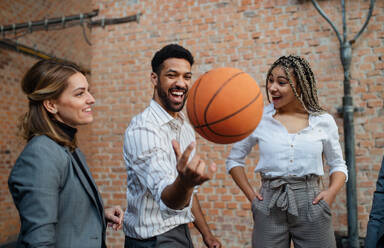 Eine Gruppe fröhlicher junger Geschäftsleute spielt Basketball im Büro und macht eine Pause. - HPIF08021