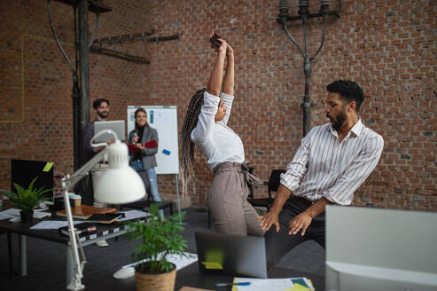 Cheerful young businesspeople having fun in office, a cooperation and brainstorming concept. - HPIF08026