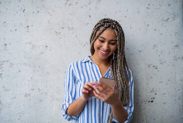 A portrait of woman freelancer standing indoors, using smarpthone. - HPIF08038