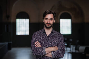 A portrait of young businessman standing indoors, looking at camera. - HPIF08050