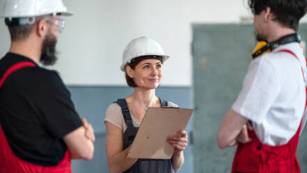 Eine Gruppe von Arbeitern mit Helm in einer Fabrik, die über Probleme diskutieren. - HPIF08136