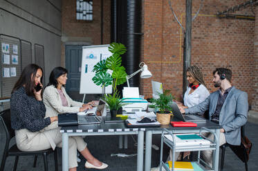 Young and old businesspeople sitting and working at desk in office, a cooperation and coworking concept. - HPIF08152