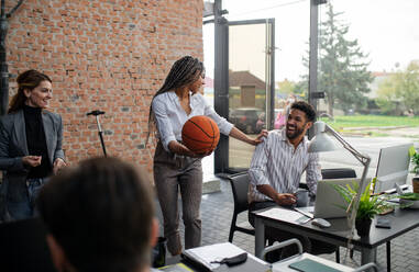 Cheerful young businesswoman having fun with a ball in office, take a break concept. - HPIF08163