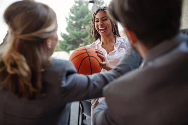 Eine Gruppe fröhlicher junger Geschäftsleute spielt Basketball im Büro und macht eine Pause. - HPIF08164
