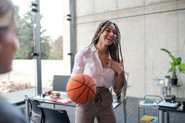 A cheerful young businesswoman having fun with ball in office, take a break concept. - HPIF08165