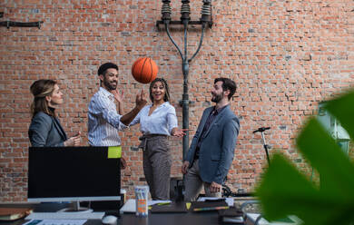 Eine Gruppe fröhlicher junger Geschäftsleute, die im Büro Basketball spielen und eine Pause einlegen. - HPIF08166