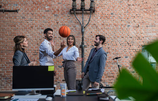 Eine Gruppe fröhlicher junger Geschäftsleute, die im Büro Basketball spielen und eine Pause einlegen. - HPIF08166