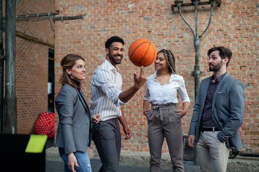 Eine Gruppe von fröhlichen jungen Geschäftsleuten spielt Basketball im Büro, Teambuilding-Konzept. - HPIF08167