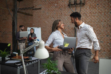 Cheerful young businesspeople having fun in office, a cooperation and brainstorming concept. - HPIF08176