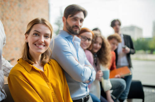 Ein Porträt einer jungen Geschäftsfrau mit einer Gruppe von Unternehmern in einem Büro, die in die Kamera schauen. - HPIF08213