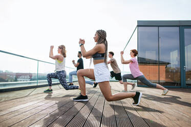 A group of young people doing exercise outdoors on terrace, sport and healthy lifestyle concept. - HPIF08223