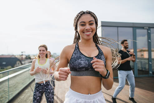 Eine Gruppe junger Menschen, die auf einer Terrasse Sport treiben, ein Konzept für Sport und gesunde Lebensweise. - HPIF08224