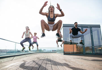 Eine Gruppe junger Menschen, die auf einer Terrasse Sport treiben, ein Konzept für Sport und gesunde Lebensweise. - HPIF08225