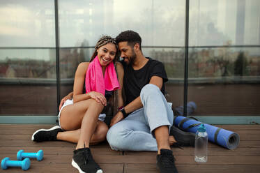 A young couple in love resting after exercise outdoors on terrace, sport and healthy lifestyle concept. - HPIF08244
