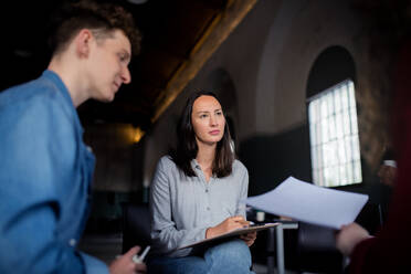 Ein Berater mit Menschen, die während einer Gruppentherapie im Kreis sitzen und sich unterhalten. - HPIF08268