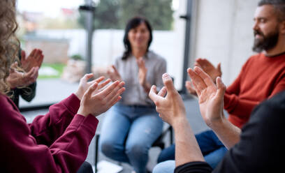 Men and women sitting in a circle during group therapy, clapping. - HPIF08283