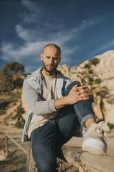 Man sitting on fence at sunset - DMGF01045