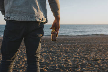 Hand eines Mannes mit Bier am Strand stehend - DMGF01063