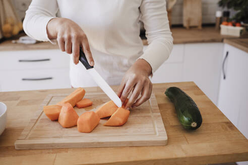 Hands of woman cutting vegetables in kitchen at home - EBBF08116