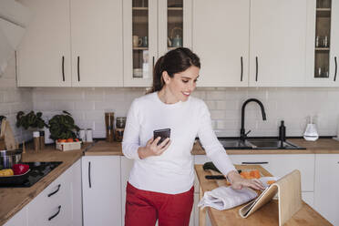 Happy woman using tablet PC in kitchen - EBBF08123