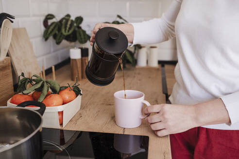 Frau gießt Kaffee in eine Tasse zu Hause - EBBF08146