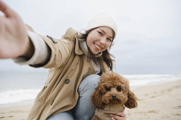 Glückliche Frau nimmt Selfie mit Hund am Strand - ALKF00167