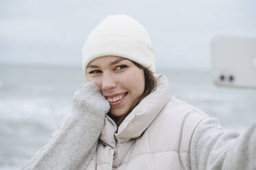 Glückliche Frau nimmt Selfie durch Smartphone am Strand - ALKF00181